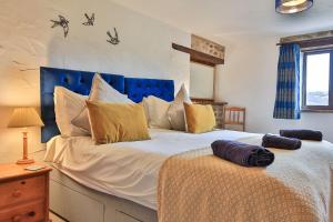 a bedroom with a large bed with a blue headboard at West Hollowcombe Farm Cottages - full site booking in Dulverton
