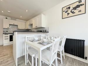 a white kitchen with a white table and chairs at Modern 2 Bedroom Apartment - Near Hospital & Racecourse in Doncaster