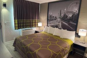a hotel room with a bed with a large picture on the wall at Super 8 by Wyndham Rockford South in Rockford