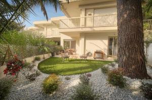 een huis met een tuin met stoelen en een boom bij Le Greg - Terrasse - Parking - VCA in Cannes