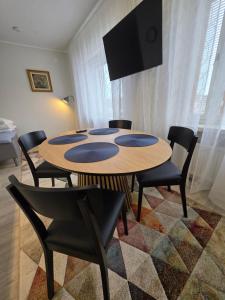 a dining room table with chairs and a flat screen tv at Yksiö kahdelle hengelle keskellä Lahtea in Lahti