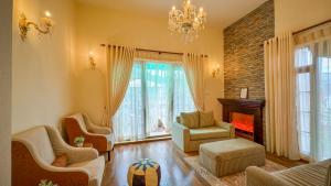 un soggiorno con camino, sedie e lampadario pendente di Alben Castle Glenfall a Nuwara Eliya
