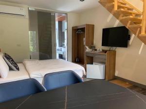 a room with a bed and two blue chairs and a tv at 百合山莊 in Nanzhuang