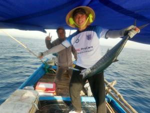 two men on a boat holding a fish in the water at Canh Tien Homestay Tam Thanh Beach in Tam Kỳ