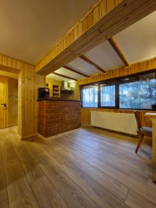 a large room with wooden floors and windows and a table at Cabana din Padurea Valeni in Vălenii de Munte