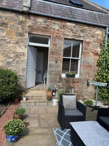 a brick house with a patio with a table and chairs at Golf Cottage in Gullane +8 photos