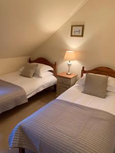une chambre avec deux lits et une lampe sur une table dans l'établissement Golf Cottage, à Gullane 8 autres photos