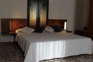 a bedroom with a large white bed with two lamps at Domus Orsoni in Venice