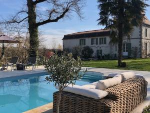 a swimming pool with a wicker couch next to a house at La Vergnotte B & B in Saint-Antoine-de-Breuilh