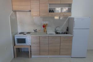a kitchen with a white refrigerator and a microwave at Golden sand apartment A in Hersonissos +2 photos