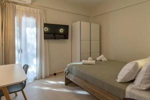 a bedroom with a bed and a table and a window at GREEN n' BLUE apartments in Kalamaki