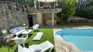 a patio with white chairs and a swimming pool at Increible casa de campo, 5 DORM, MARCO INCOMPARABLE in Pareja