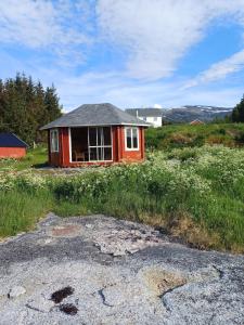 a small red house in a field of grass at seafront villa in Dragland +64 photos