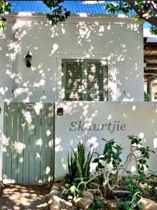 een wit gebouw met een poort en een raam bij Skuurtjie in Prince Albert