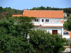 a white house with an orange roof and some trees at Apartments "Sun-sea" in Rab