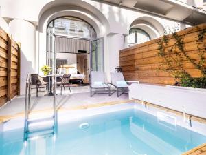 a swimming pool in the middle of a patio with a table and chairs at The 1932 Hotel & Spa Cap d'Antibes - MGallery Collection in Juan-les-Pins +37 photos