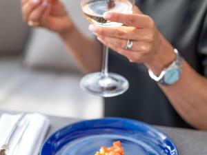 a person holding a wine glass next to a plate of food at The 1932 Hotel & Spa Cap d'Antibes - MGallery Collection in Juan-les-Pins