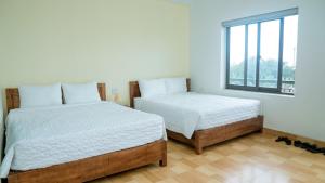 two beds in a white room with a window at Tam Coc Gold Smile Homestay in Vũ Lâm