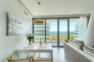 Una sala de estar con un sofá y una mesa con flores. en Your Holidays Waves D648 z widokiem na morze, en Międzyzdroje