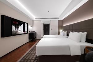 a bedroom with a large white bed and a flat screen tv at Intercity Jinghong Xishuangbanna in Jinghong