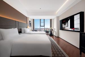 a hotel room with a large bed and a flat screen tv at Intercity Jinghong Xishuangbanna in Jinghong