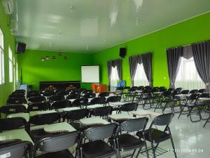 an empty room with green walls and tables and chairs at Esemka Hotel and Convention Kotabumi in Kotabumi