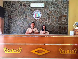 two people sitting at a counter with their hands up at Esemka Hotel and Convention Kotabumi in Kotabumi