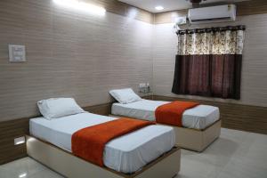 two twin beds in a room with a window at HOTEL VALLABHA RESiDENCY in Rājahmundry