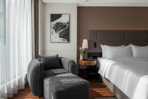 a hotel room with a bed and a chair at Intercity Jinghong Xishuangbanna in Jinghong