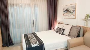 a bedroom with a bed and a chair and a window at Elio Del Ray Studio walk to BTS in Bangkok +37 photos
