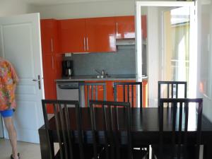 a kitchen with red cabinets and a black table and chairs at Terrasses des Embiez in Six-Fours-les-Plages +8 photos