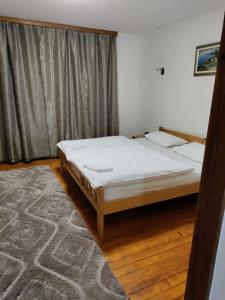 a bedroom with a bed with white sheets and a rug at Luni in Travnik