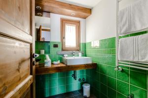 a green tiled bathroom with a sink and a mirror at Villa Rosa di Nonna Rosa in Vico Equense