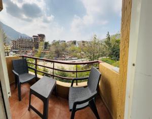 two chairs and a table on a balcony with a view at Luxury Aloha Majestic Apartments in Rishīkesh