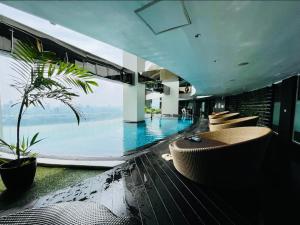 a hotel lobby with a pool with chairs and a palm tree at The Gramercy Residences NEW Sleek 1BR Suite, 600mbps Wifi, Netflix & FREE Amenities in Manila