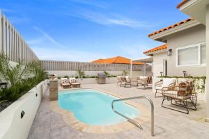 a swimming pool in a yard with chairs and a house at 3BR Private Pool Retreat 4 Mins Drive by Bocobay in Palm-Eagle Beach