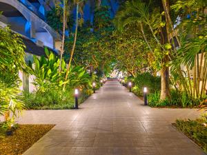 a walkway lined with trees and lights at night at Pooh Beach Resort & Spa in Jomtien Beach