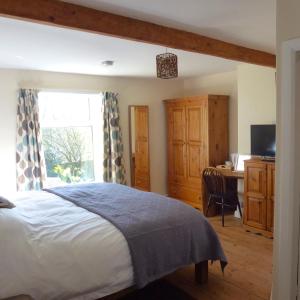 a bedroom with a bed and a desk and a window at Manor Farm Stay in Sutton on Sea