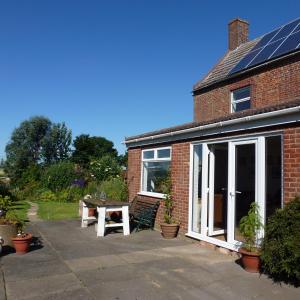 a brick house with a patio with a table at Manor Farm Stay in Sutton on Sea