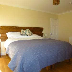 a bedroom with a large bed with a wooden headboard at Manor Farm Stay in Sutton on Sea