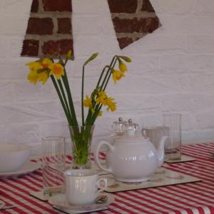 a table with a tea pot and flowers in a vase at Manor Farm Stay in Sutton on Sea