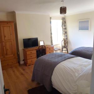 a bedroom with a bed and a desk with a television at Manor Farm Stay in Sutton on Sea