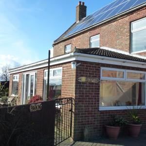 a brick house with a fence in front of it at Manor Farm Stay in Sutton on Sea
