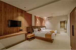 コーリコードにあるHotel Beverly Plaza Kozhikodeのベッドと薄型テレビのある寝室