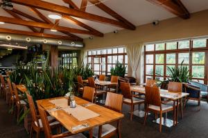 a restaurant with wooden tables and chairs and plants at Hotel Golf Resort Olomouc in Dolany