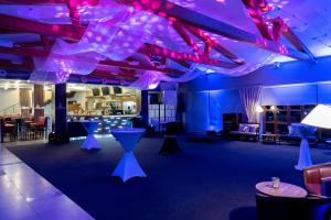 a room with purple lighting and tables and chairs at Hotel Golf Resort Olomouc in Dolany