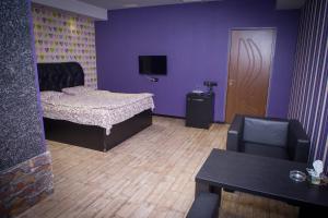 a room with a bed and a chair and a tv at Palazzo Hotel in Yerevan