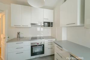 a kitchen with white cabinets and a stove top oven at Flexliving - room - Turbigo in Paris