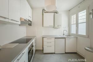 a kitchen with white cabinets and a sink and a window at Flexliving - room - Turbigo in Paris