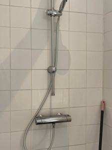 a shower with a hose on a white tiled wall at Studio Gerenoveerde winkel in Arnhem +14 photos
